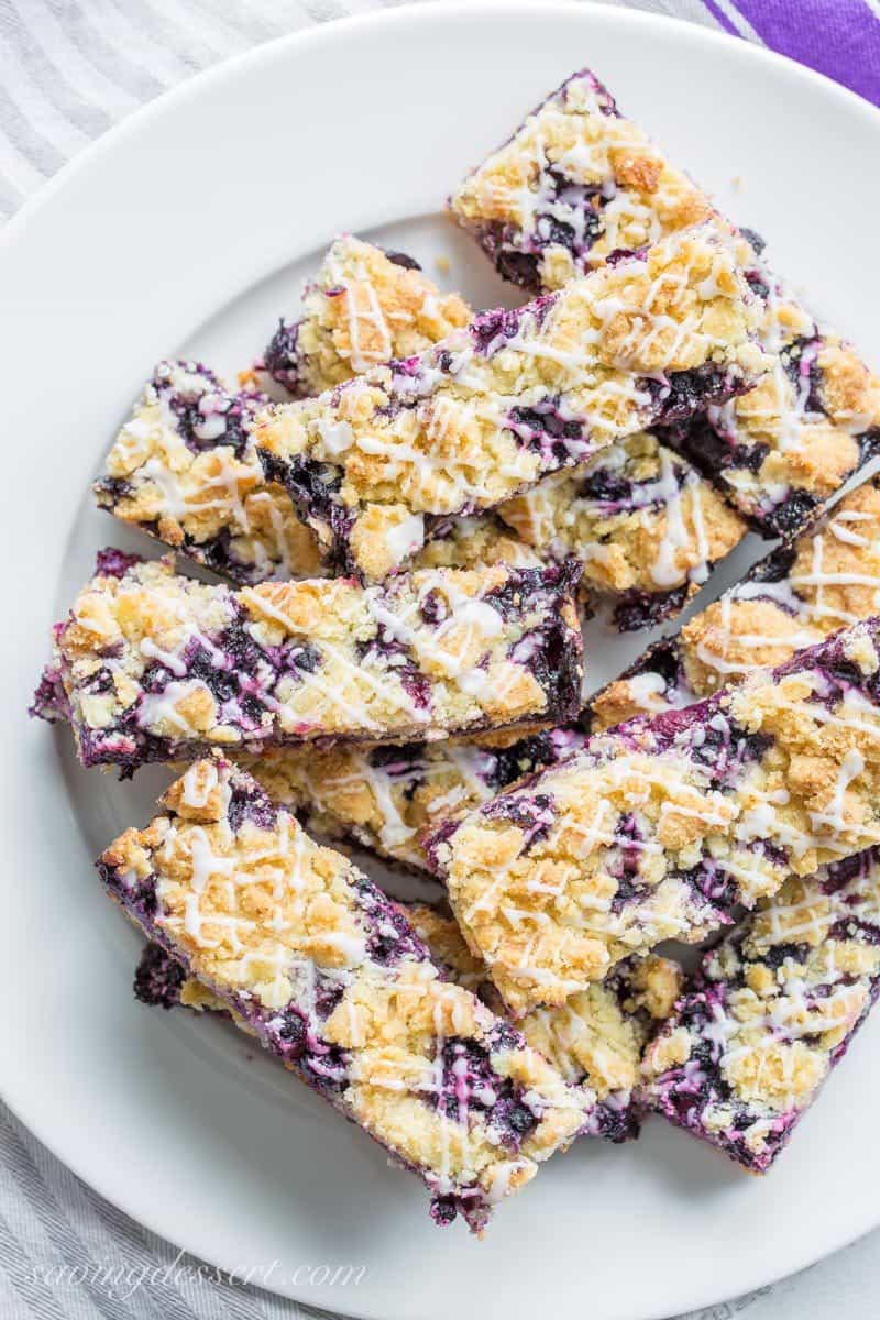 A plate of blueberry bars with a crumb topping and a drizzle of icing