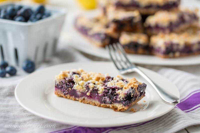A fresh blueberry crumb bar on a plate with a fork