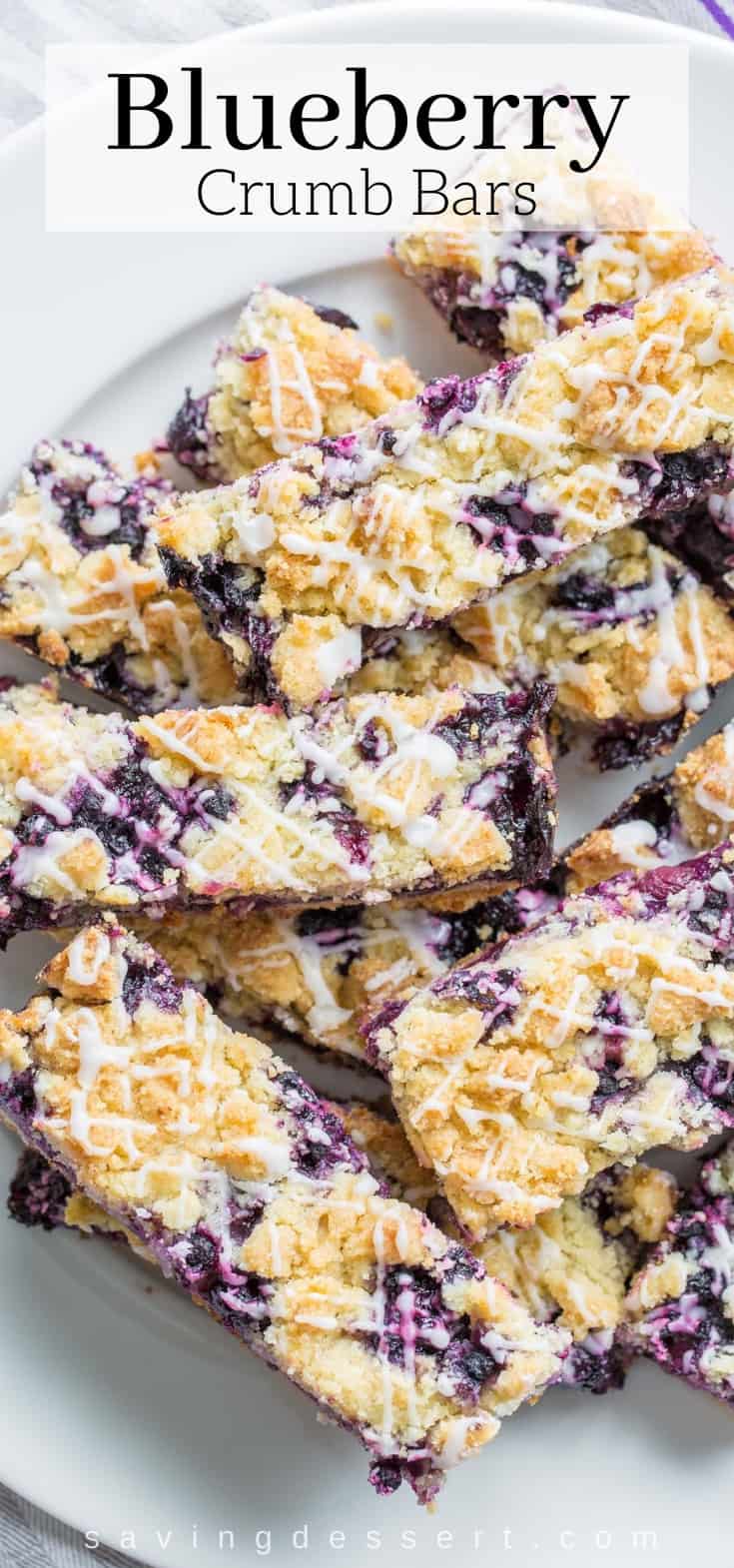 An overhead view of a plate of blueberry crumb bars drizzled with a lemon icing