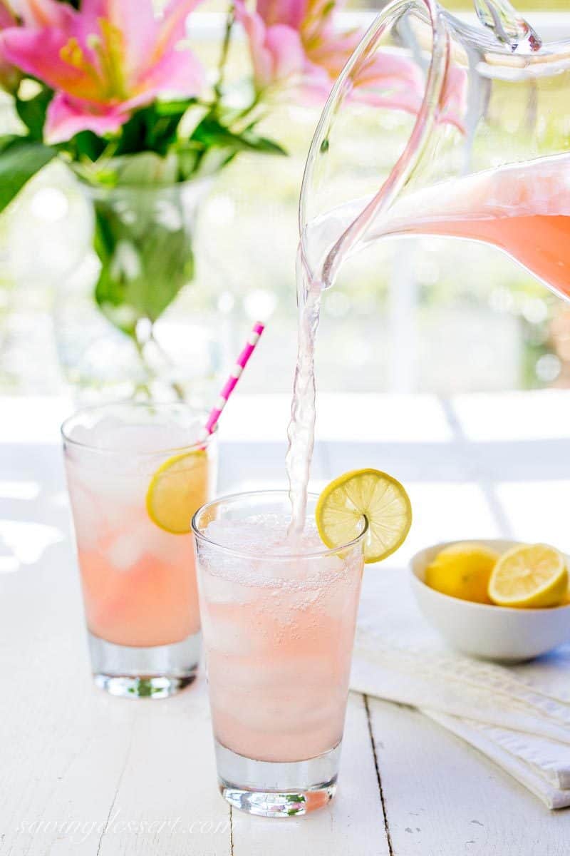 Glasses of pink lemonade with fresh lemons as a garnish