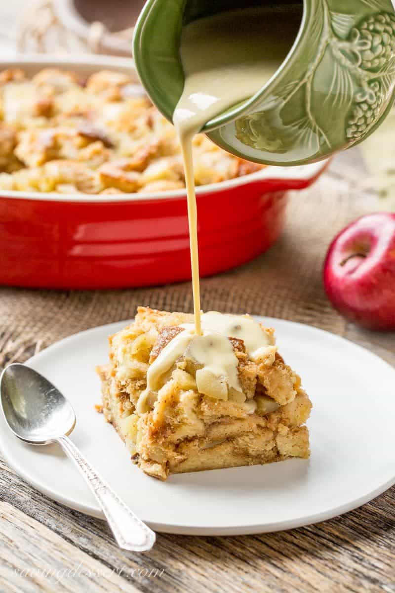 A slice of bread pudding on a plate being drizzled with an apple brandy cream sauce