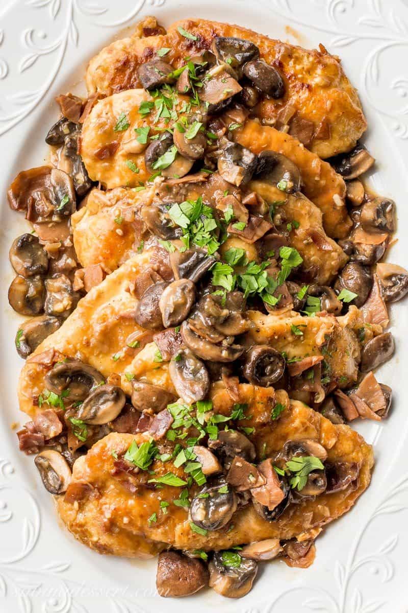Classic Chicken Marsala ~ tender chicken breasts are seasoned and sautéed, then simmered in a Marsala wine sauce with shallots, prosciutto, and plenty of earthy mushrooms. Your guests never have to know how easy this is to make! savingdessert.com #chickenmarsala #chickendish #chicken #chickenmushrooms #marsala