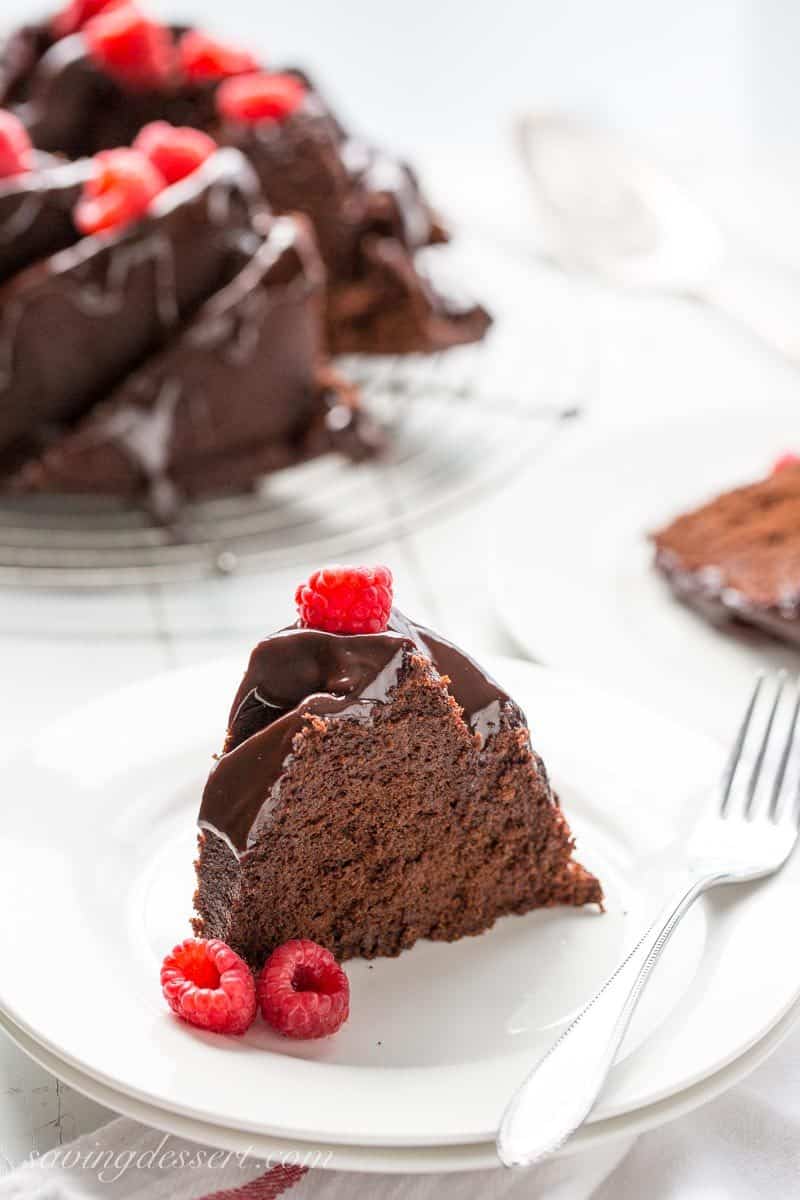 A slice of chocolate cake on a plate served with fresh raspberries