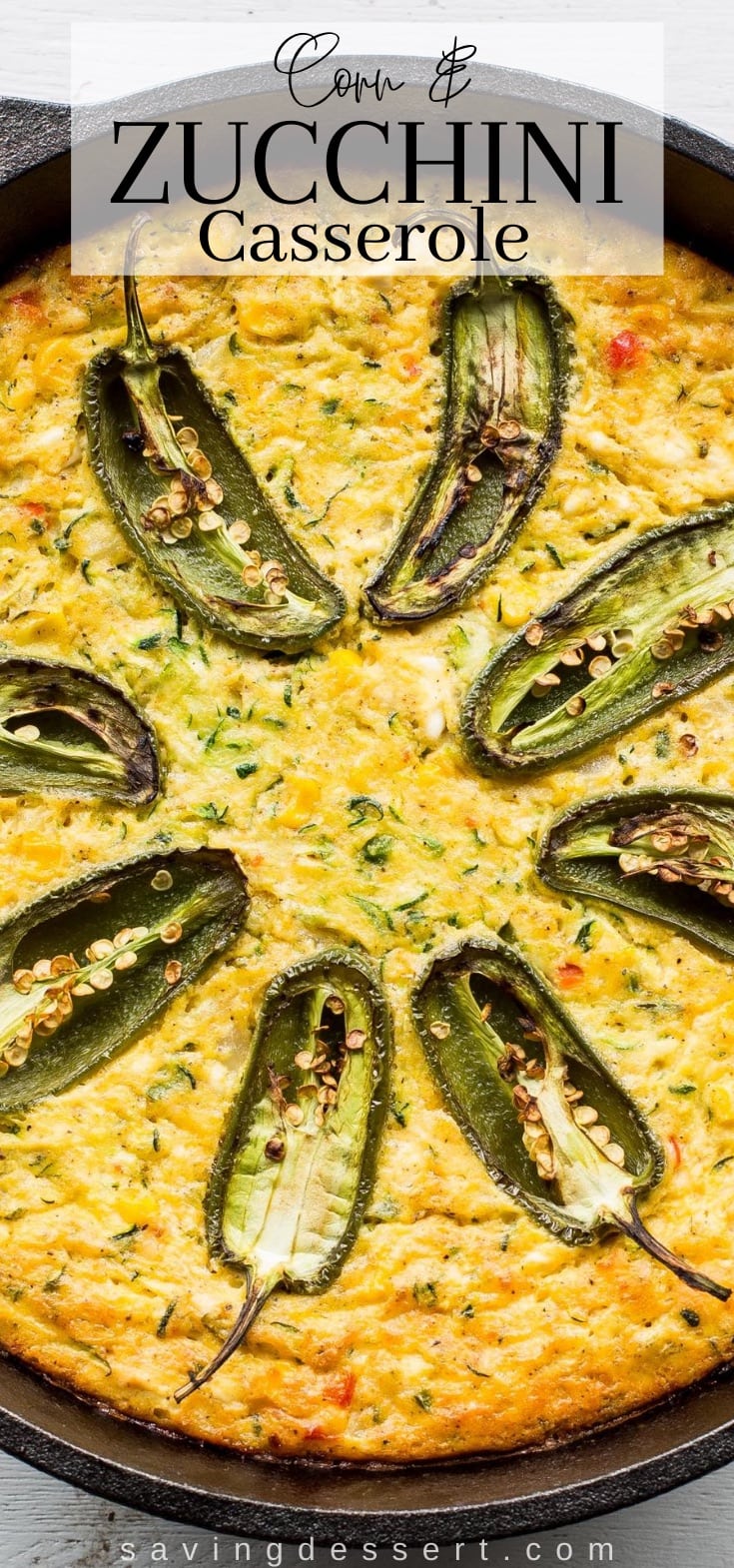 A cast iron pot filled with a corn and zucchini casserole topped with jalapeño peppers