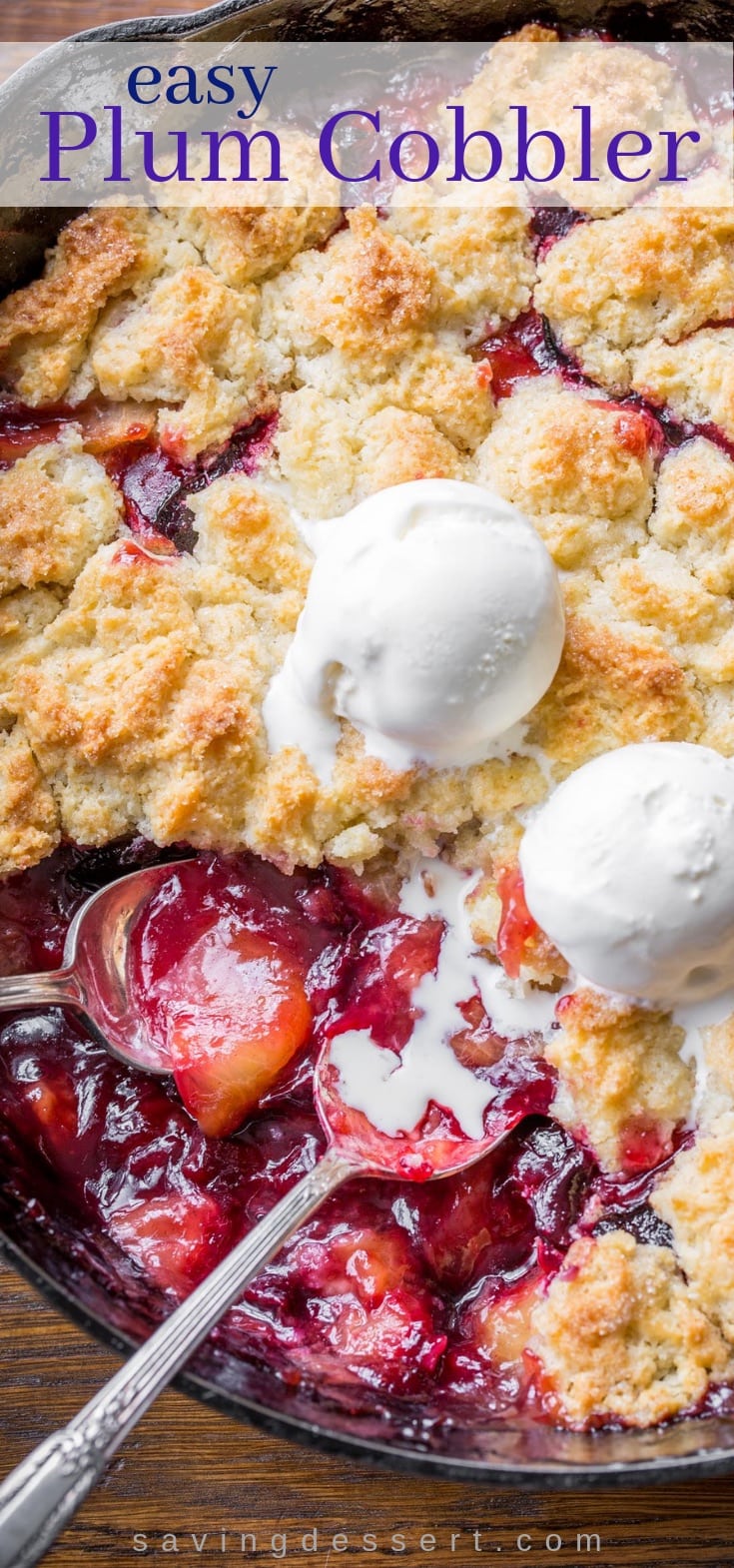 A skillet with fresh plum cobbler topped with scoops of vanilla ice cream