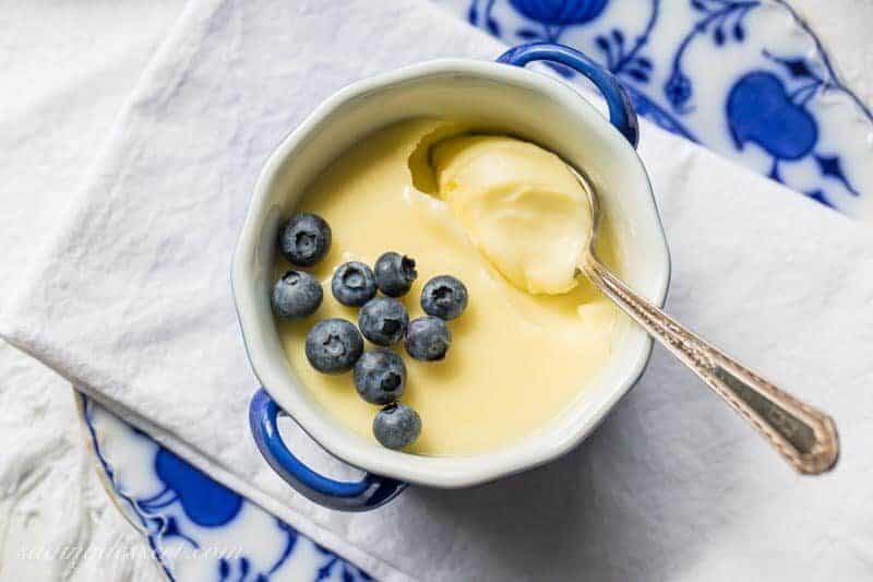 An overhead view of a bowl of lemon posset topped with blueberries