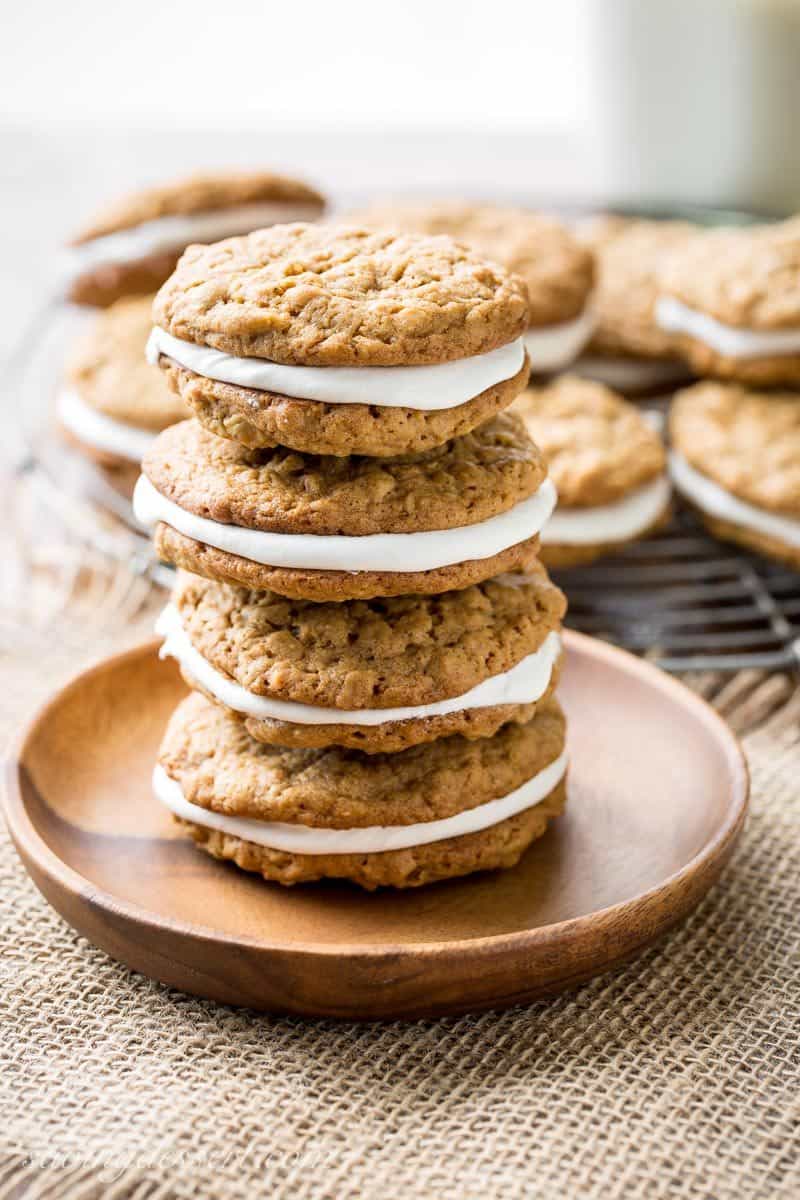 A stack of filled oatmeal cookies on a wooden plate