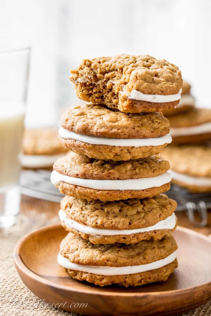 Oatmeal Cream Pies stacked on a wood plate with a bite out of the top cookie