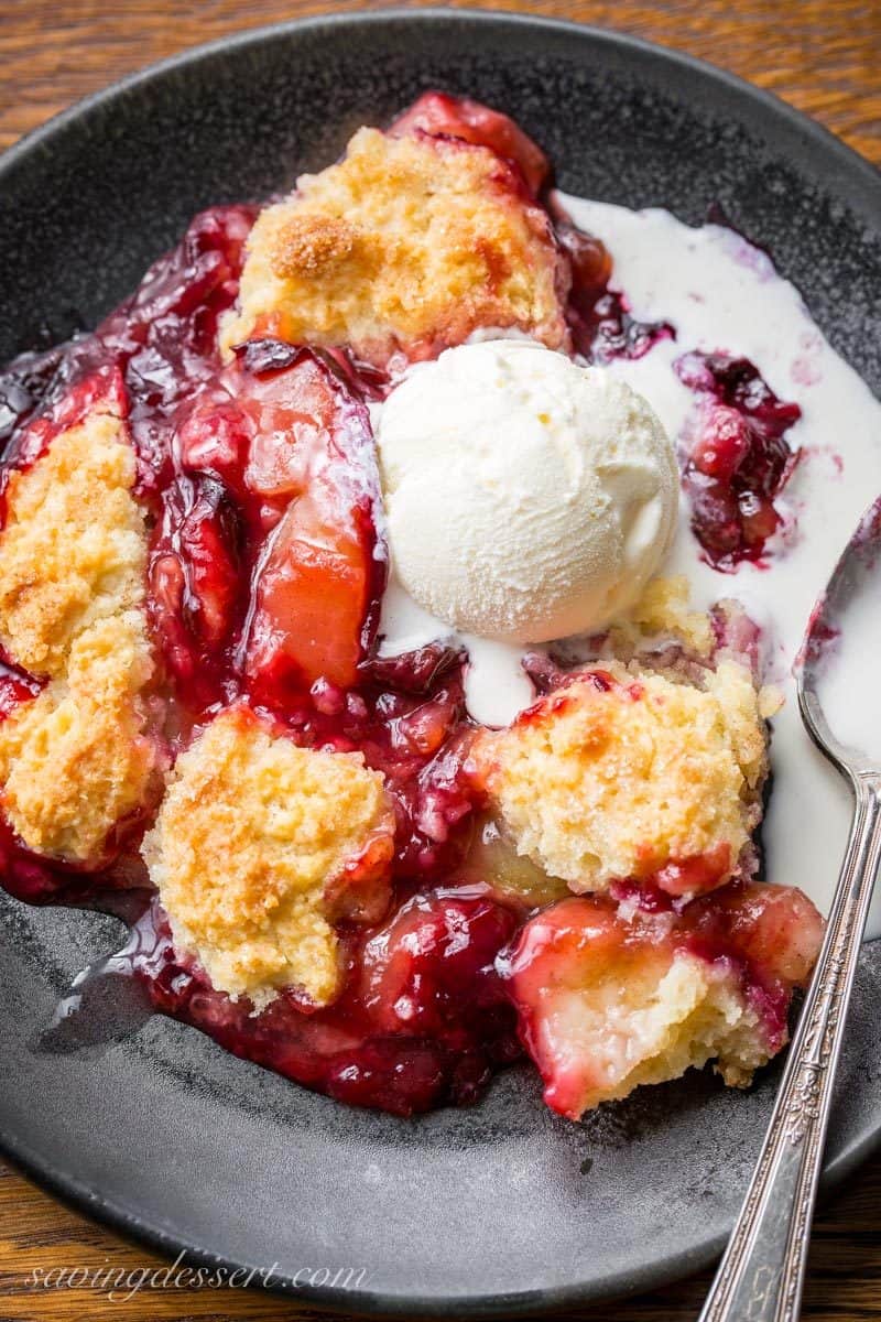 A plate filled with Plum Cobbler topped with vanilla ice cream