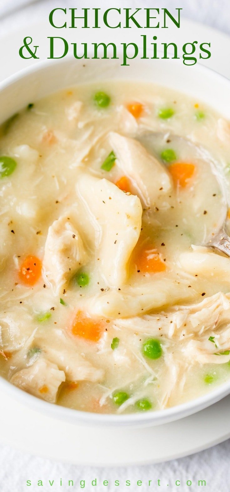 A bowl of chicken and dumplings with carrots, peas and plenty of black pepper