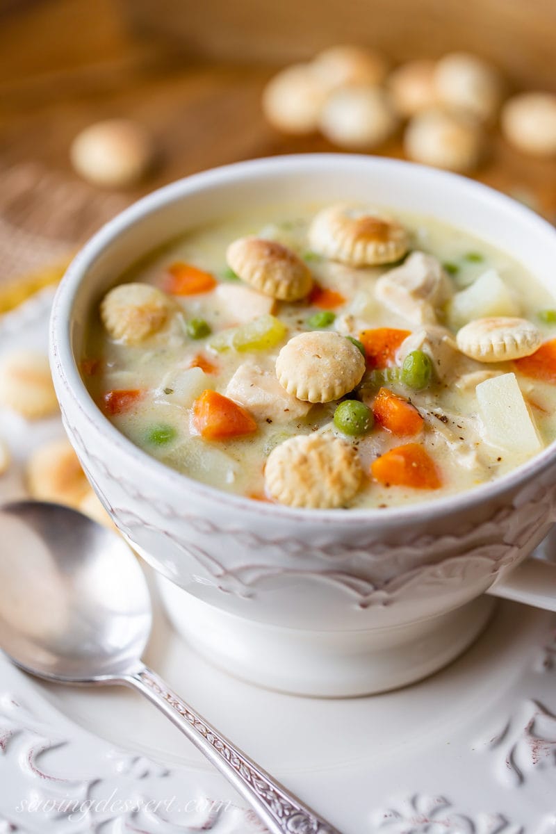 A bowl of chicken pot pie soup with oyster crackers on top