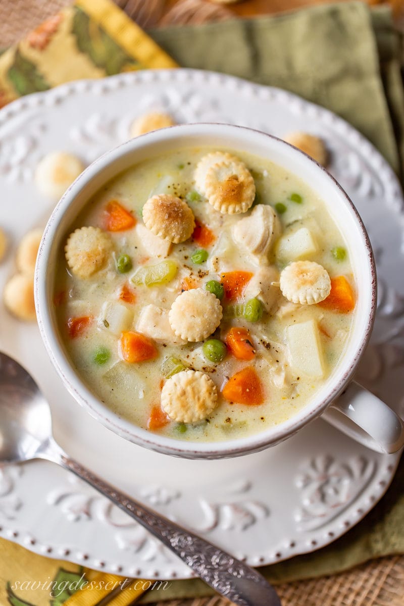 A bowl of hearty chicken pot pie soup with carrots, potatoes, peas and oyster crackers