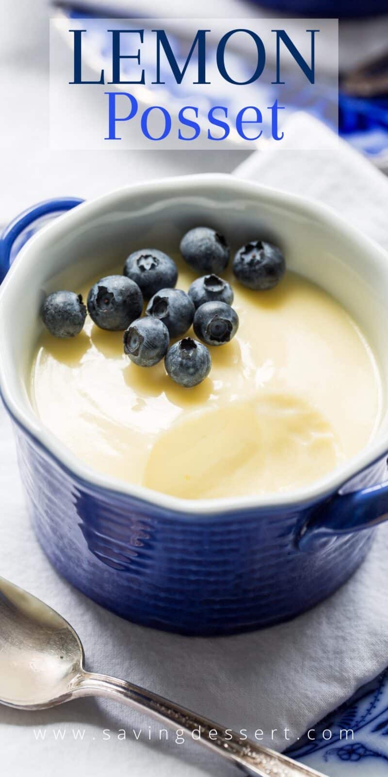Overhead view of a small blue bowl filled with lemon posset with blueberries on top