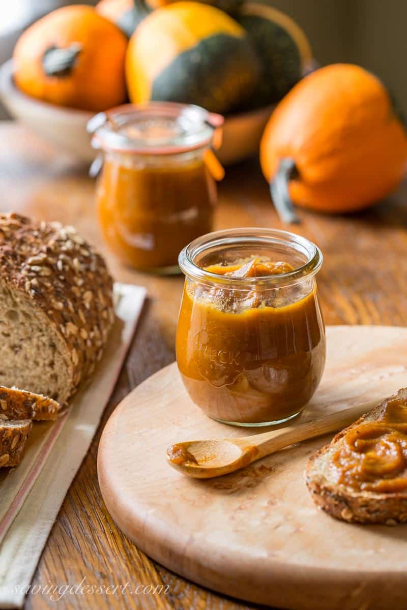 Jars of pumpkin butter with pumpkins and seeded wheat bread