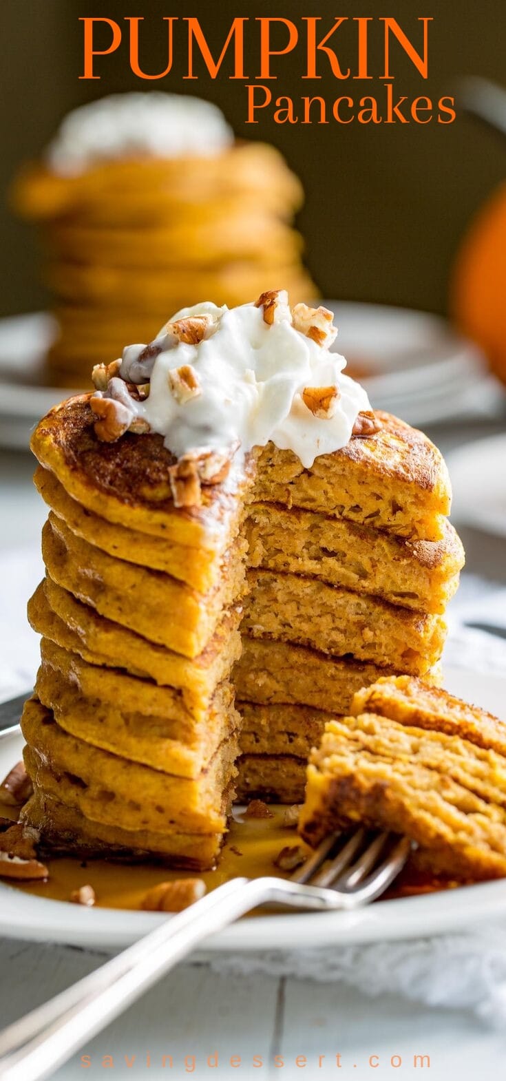 A stack of pumpkin pancakes topped with whipped cream and chopped pecans.