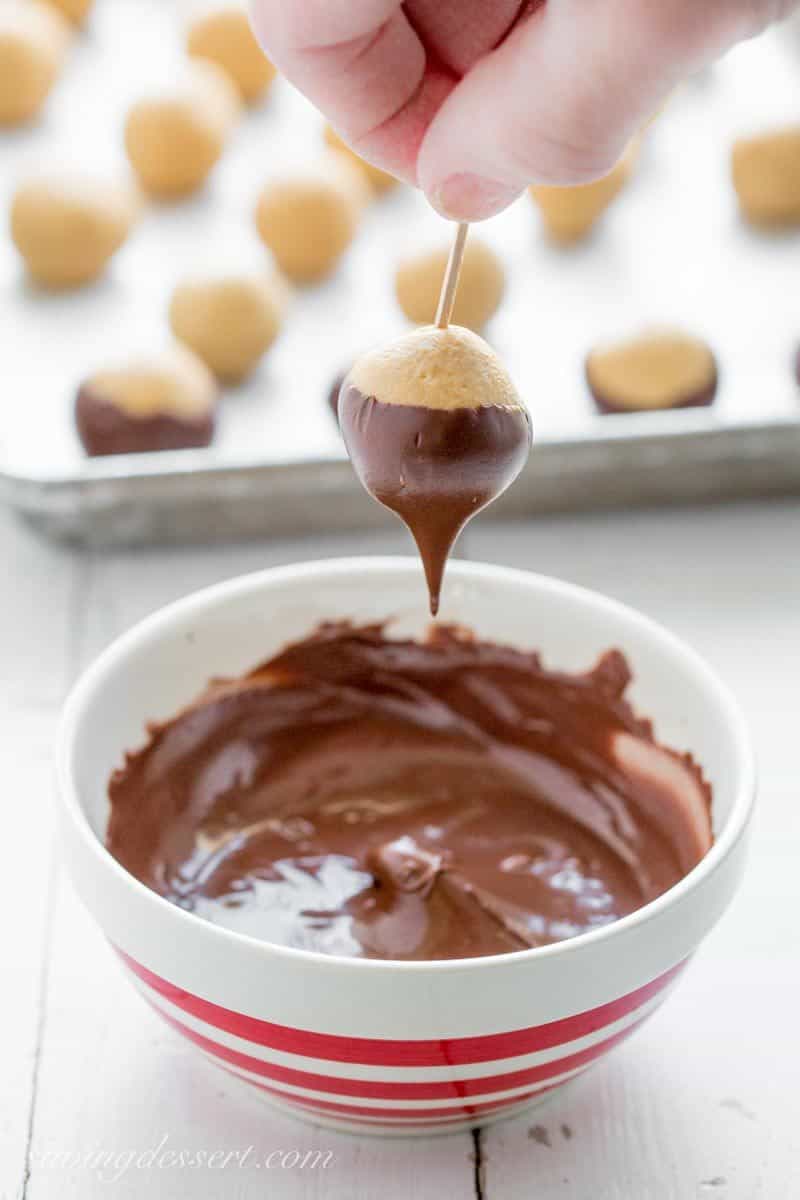 Peanut Butter Buckeye Candy ~ creamy, sweet peanut butter dough balls are partially dipped in chocolate to mimic the fruit of the Ohio Buckeye tree. www.savingdessert.com #savingroomfordessert #buckeyes #peanutbutterballs #christmascandy #buckeye