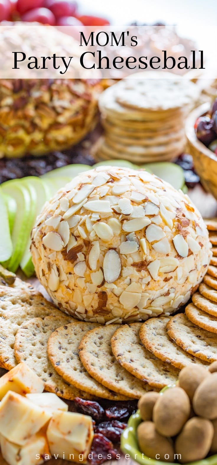 A cheeseball covered in sliced almonds on a platter of crackers, fruit, nuts and cheese