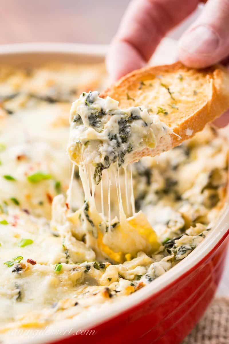A cheesy spinach and artichoke dip served with toasted bread slices