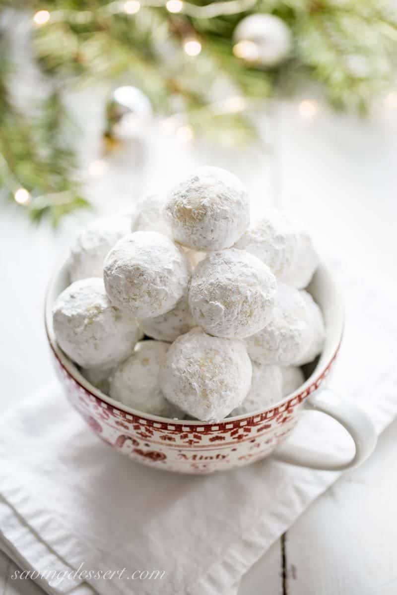 An overhead view of a bowl of Russian Tea Cakes coated with powdered sugar.