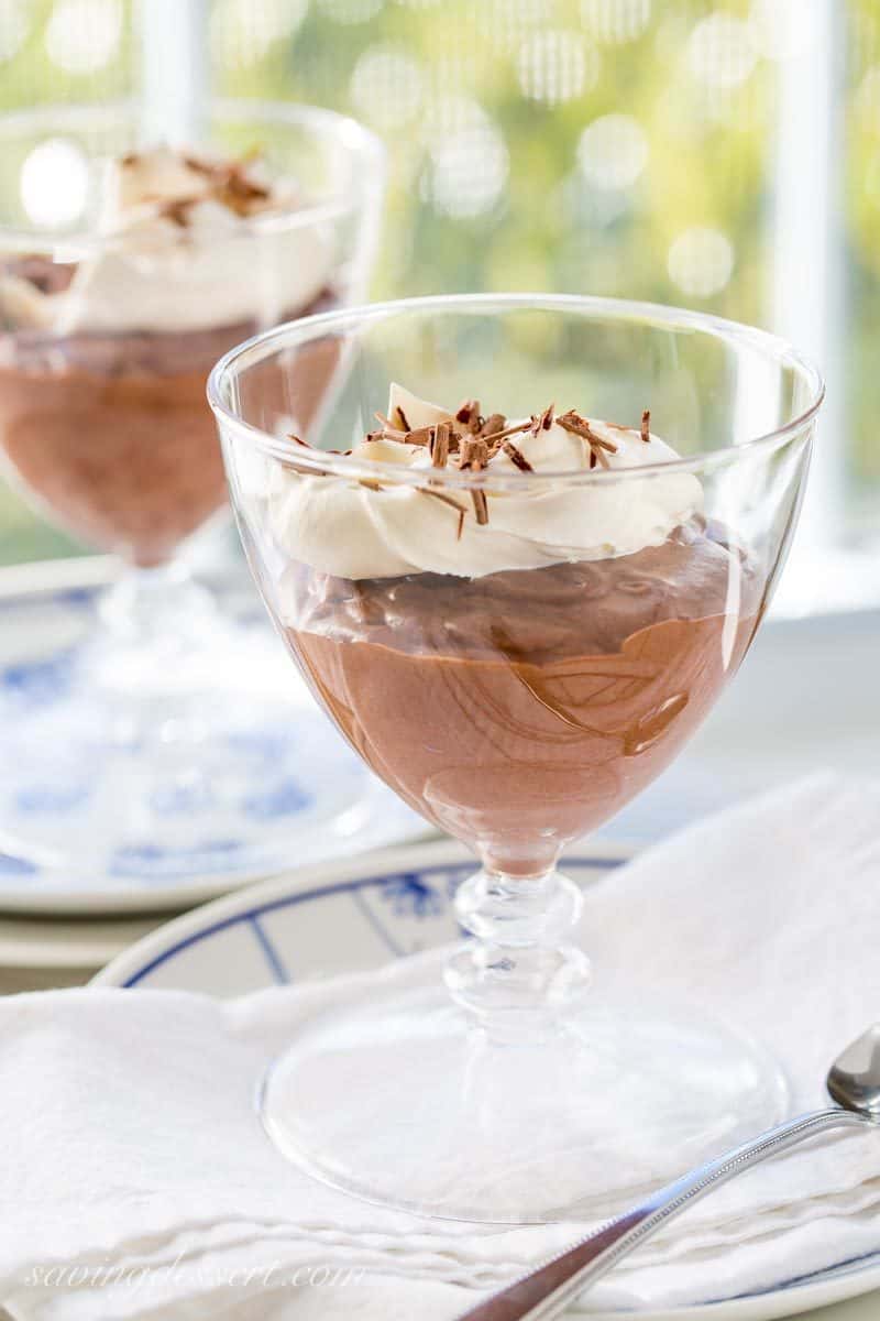 Glasses filled with chocolate mousse topped with whipped cream and shaved chocolate curls