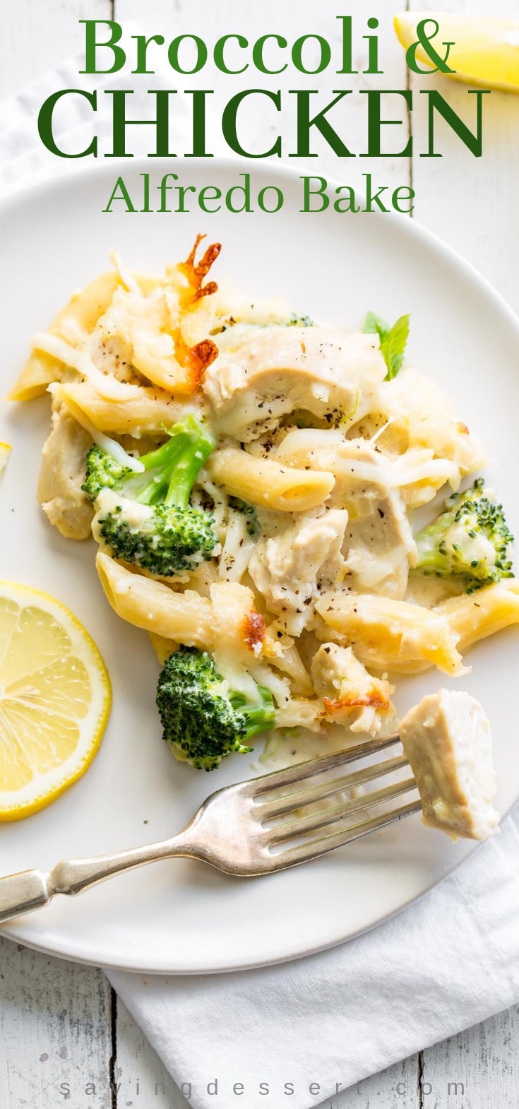 A plate with broccoli and chicken Alfredo with slices of lemon on the side