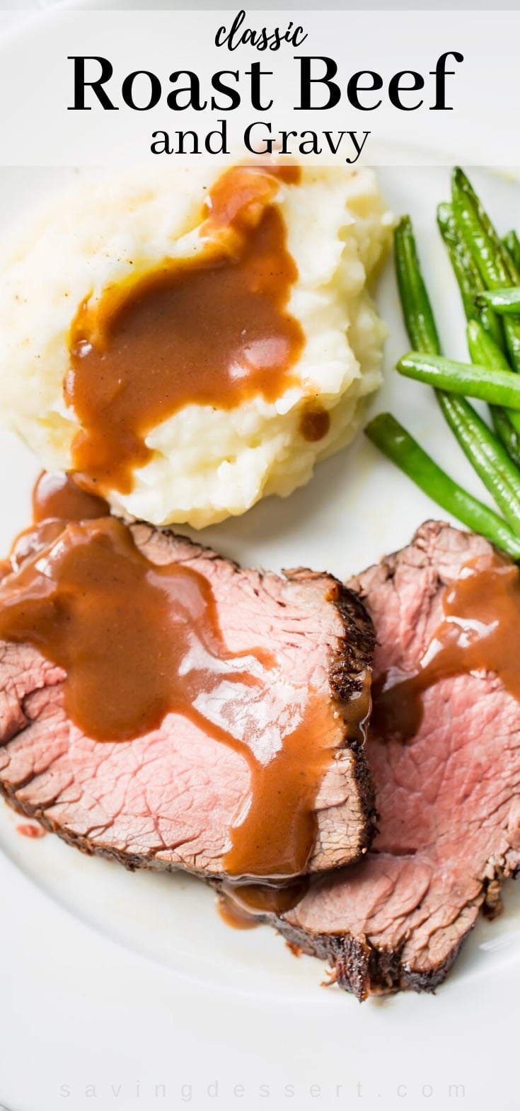 A plate filled with classic roast beef and gravy with mashed potatoes and green beans