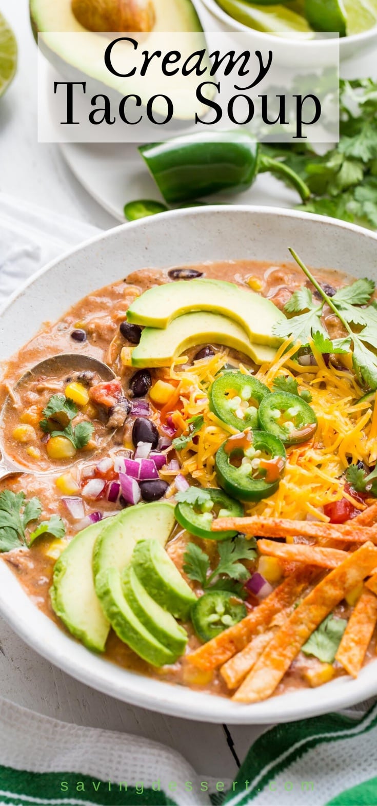 A bowl of creamy taco soup with cheese, chips, avocado and jalapeños
