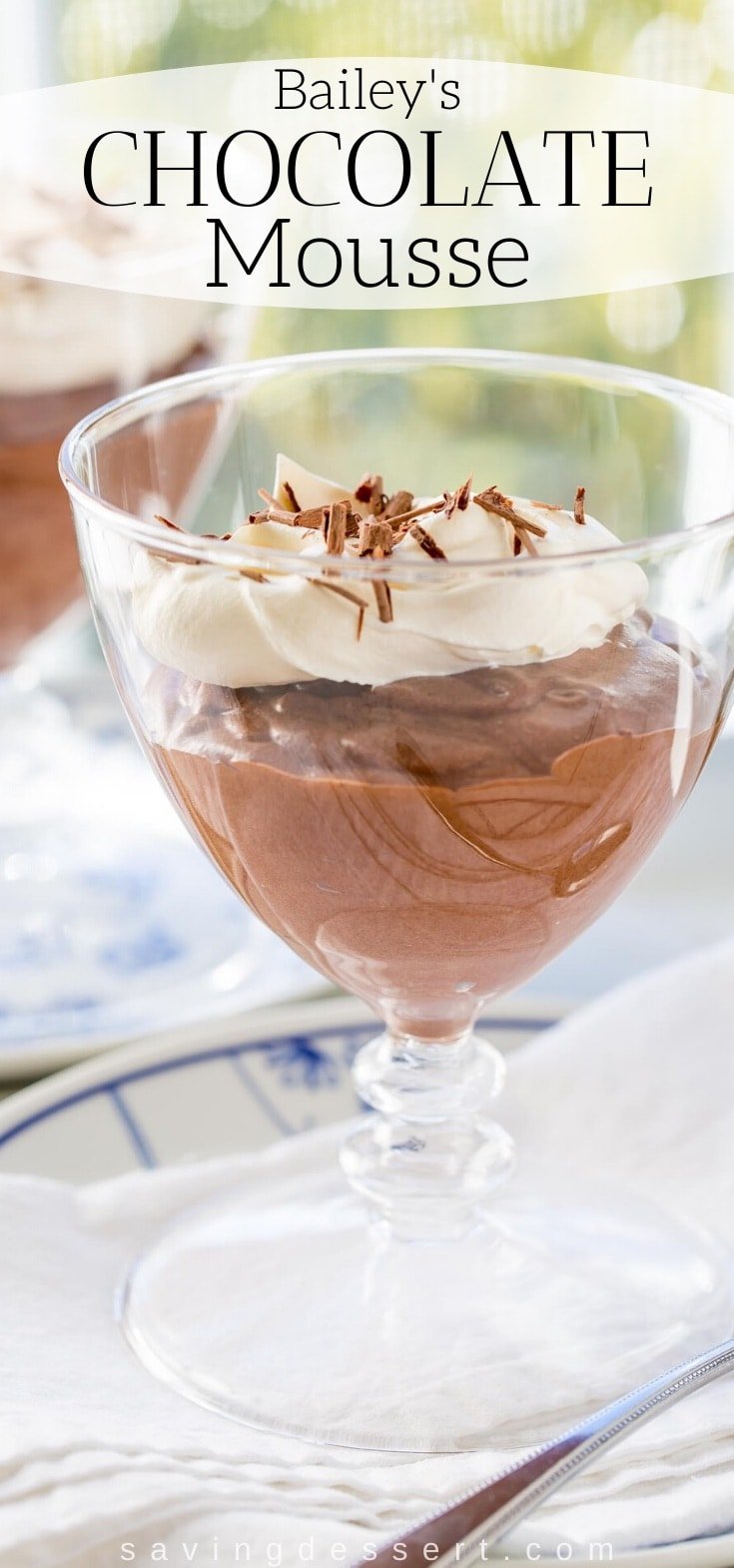 A glass filled with light chocolate mousse topped with whipped cream and grated chocolate