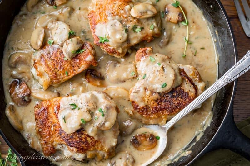 Cast iron skillet with chicken thighs in a mushroom herb pan sauce