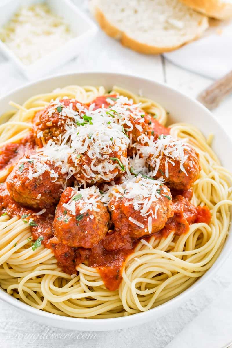 A bowl of spaghetti topped with Italian meatballs and cheese