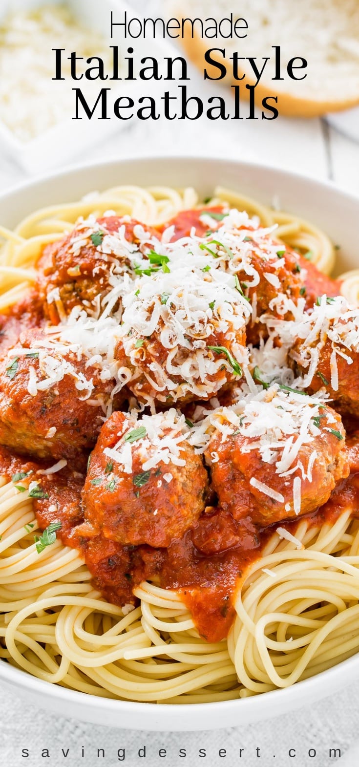 Homemade Italian Meatball recipe served over a bowl of spaghetti covered with fresh grated Parmesan