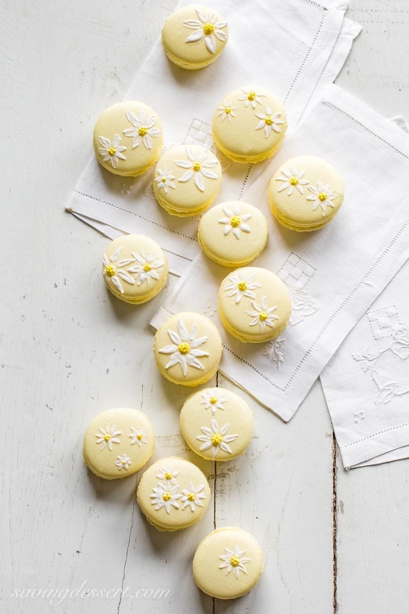 Pretty yellow macaron cookies painted with daisies using royal icing