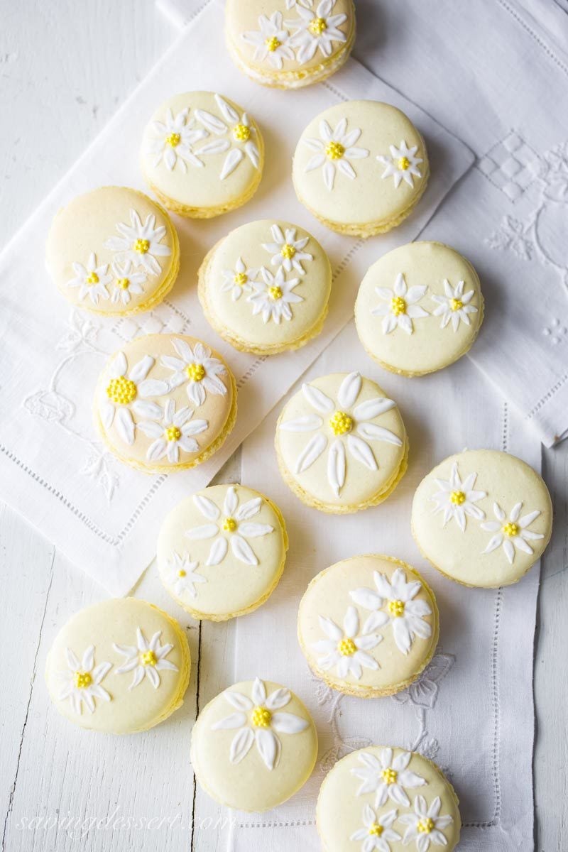 Pretty yellow macaron cookies painted with daisies using royal icing