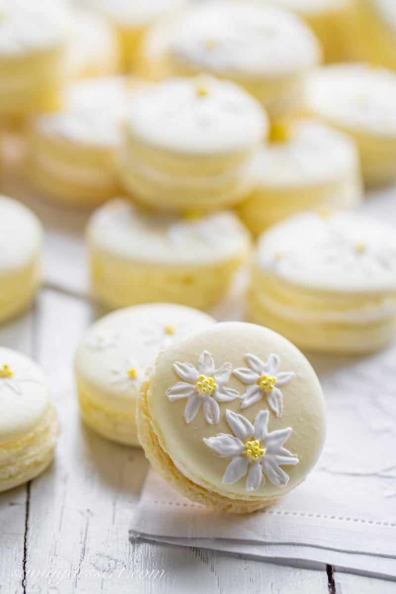 Pretty yellow macaron cookies painted with daisies using royal icing