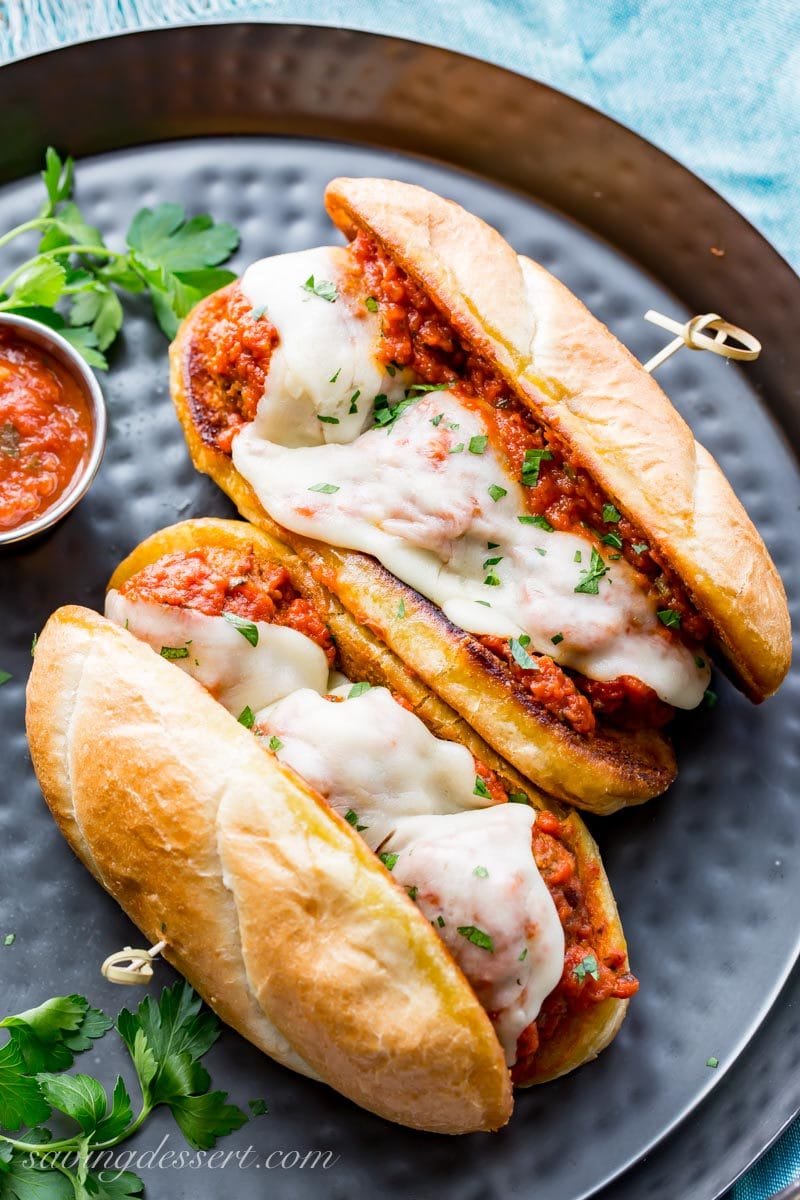 Two meatball sub sandwiches on a platter topped with melted cheese