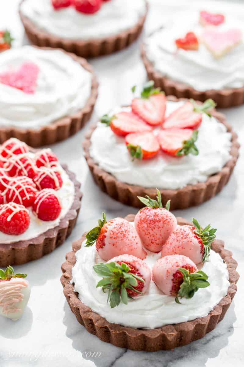 Chocolate Tarts with White Chocolate Mousse filling topped with sprinkle hearts, strawberries and raspberries