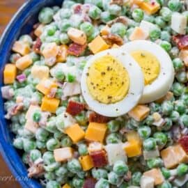 A bowl of pea salad with sliced hard boiled eggs on top
