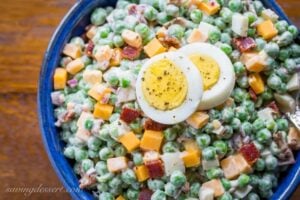 A bowl of pea salad with sliced hard boiled eggs on top