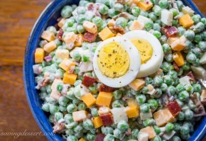 A bowl of pea salad with sliced hard boiled eggs on top