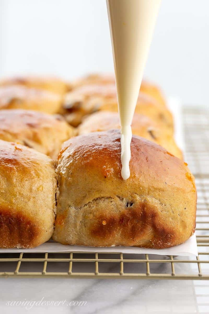 A sweet bun being iced with a piping bag