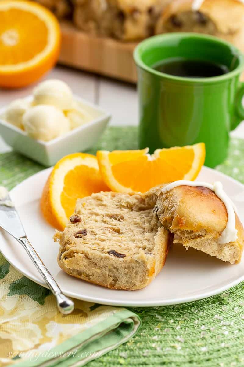 a raisin filled bun sliced in half on a plate with oranges and butter