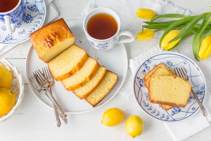 lemon ricotta pound cake sliced, with lemons, tea and yellow tulips