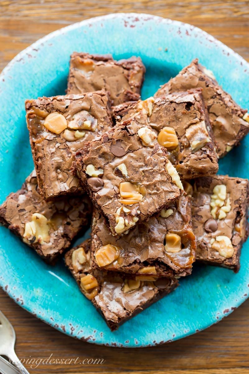 A plate of chocolate brownies with walnuts, chocolate chips and caramel