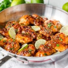 A skillet with chicken and limes
