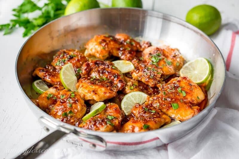 A skillet with chicken and limes