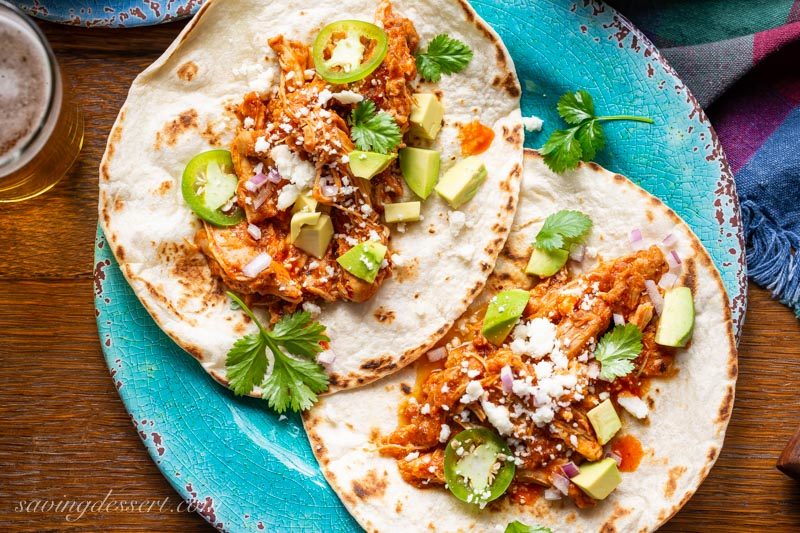 shredded chicken tinga tacos with avocado, tomatoes, jalapeño peppers, cilantro and crumbled Cojita cheese