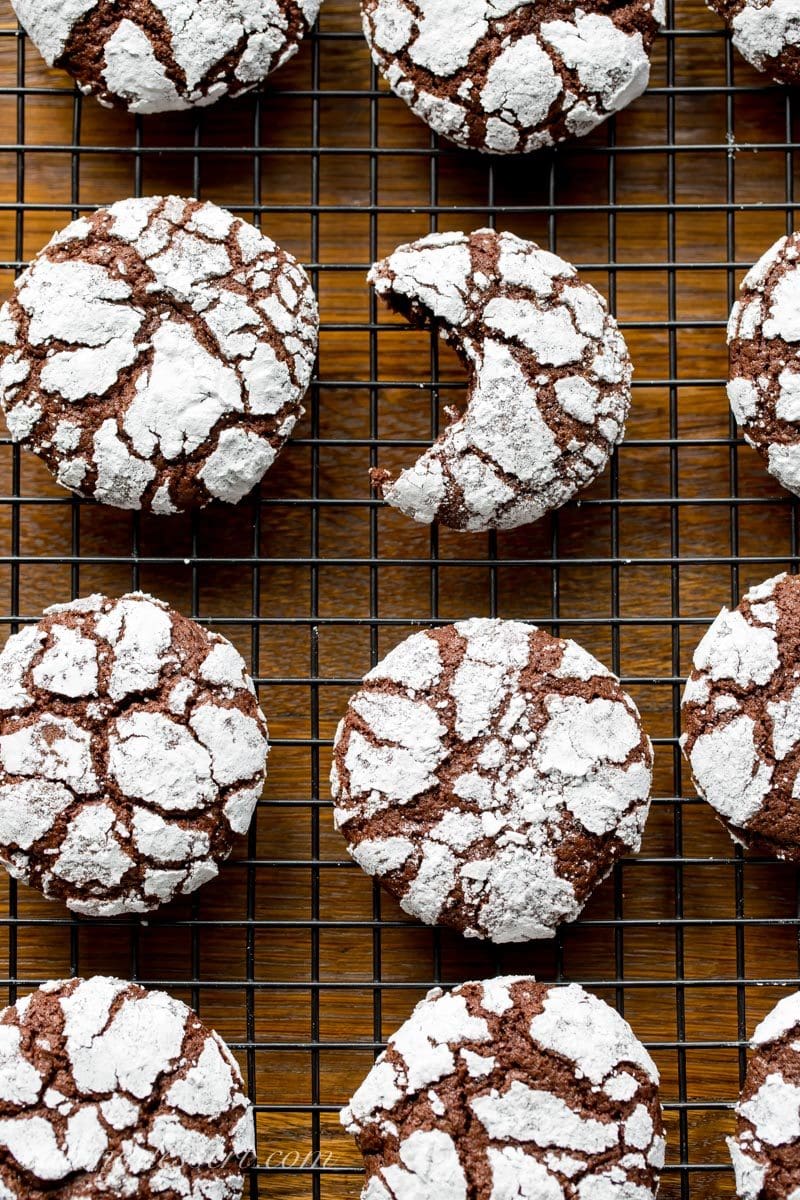 a cooling rack with Chocolate Crinkle Cookies covered in powdered sugar
