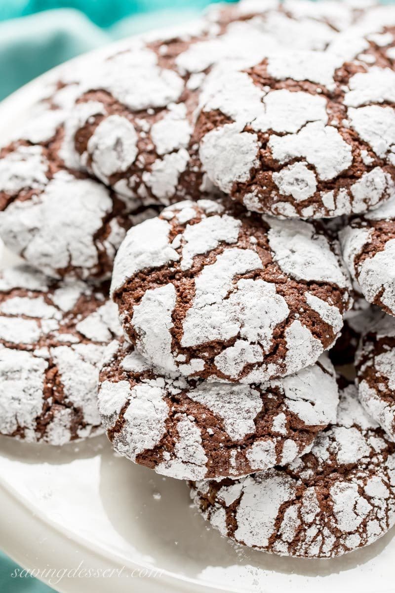 An overhead view of chocolate cookies covered in powdered sugar on a cake platter
