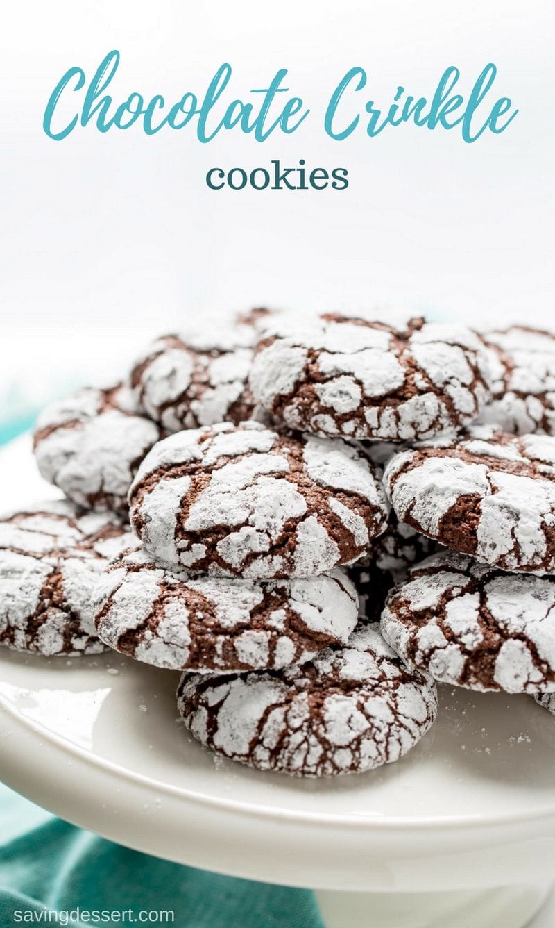 A cake platter stacked with chocolate crinkle cookies