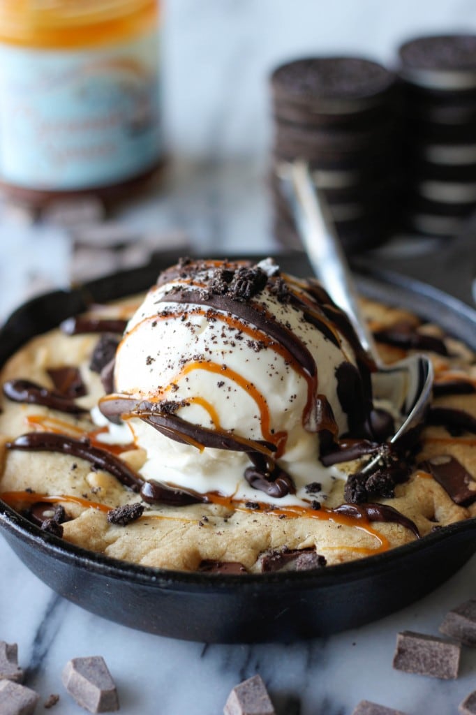 Copycat Brown Butter Chocolate Chip Cookie Skillet ("Pizookie") topped with ice cream, chocolate and caramel with a spoon